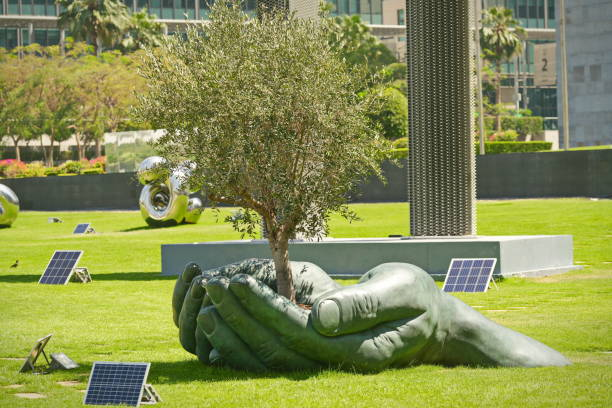 Rows of tall palm trees under a blue sky in one of the green spaces of Emaar Valley Phase 2.