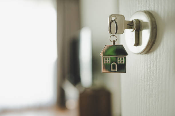 A house-shaped keychain hangs from a key inserted into a door lock.