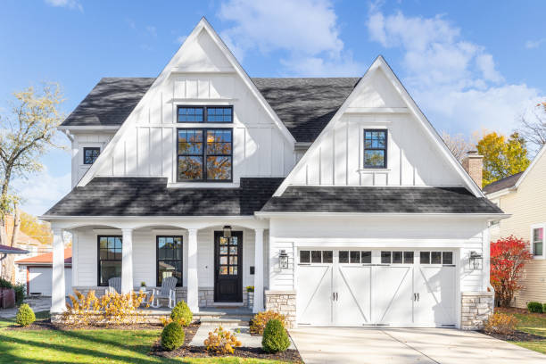 A modern white two-story house with large windows and a double garage under a clear blue sky.